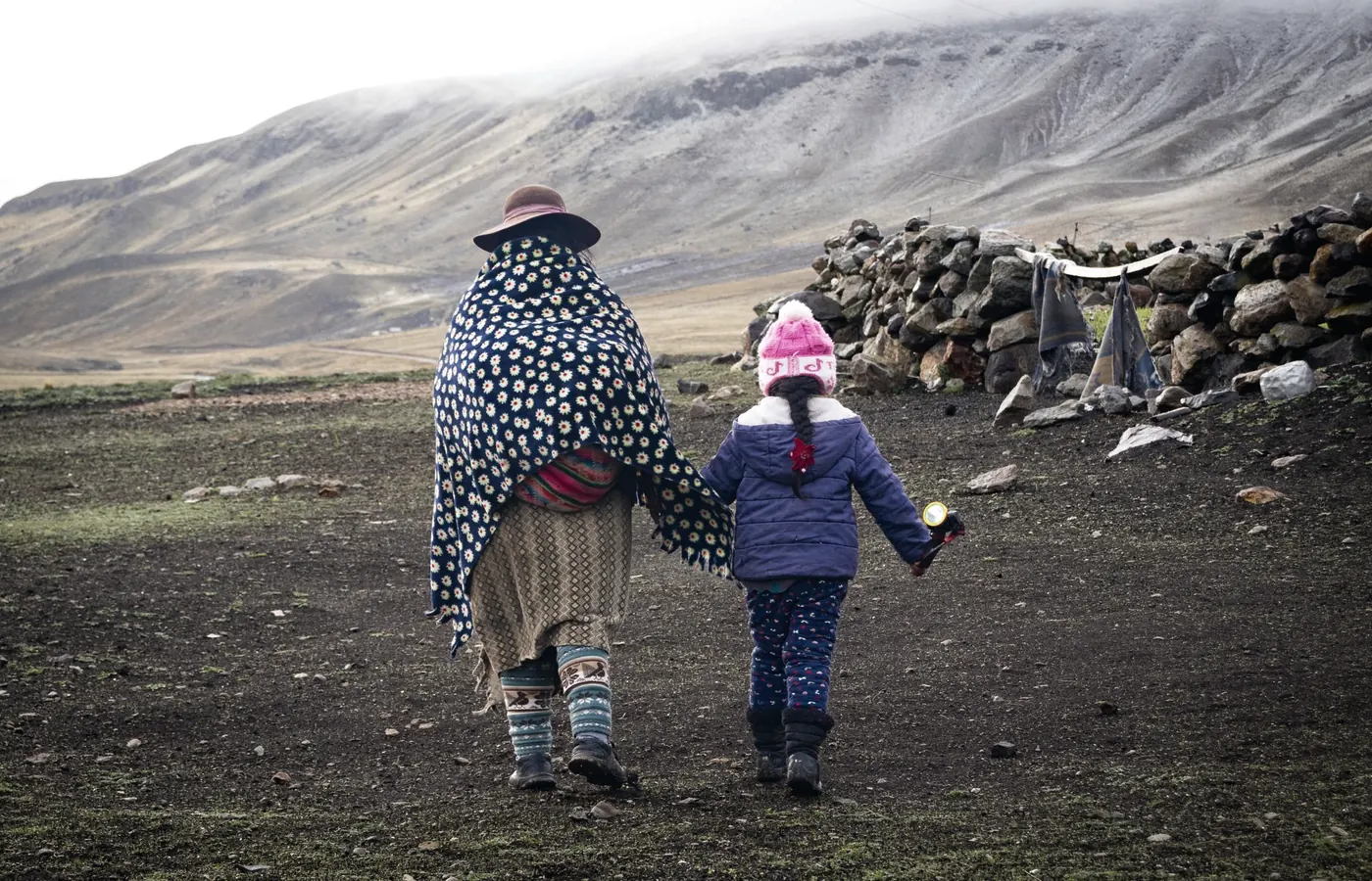 Una madre camina de la mano con su hija por un sendero
